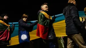 Lietuvos gyventojai susirinkę palaikyti Ukrainos, laikydami didelę Lietuvos trispalvę vėliavą Vilniuje.