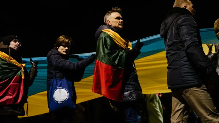 Lietuvos gyventojai susirinkę palaikyti Ukrainos, laikydami didelę Lietuvos trispalvę vėliavą Vilniuje.