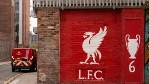 Raudona siena su Liverpulio futbolo klubo simbolika ir Čempionų lygos taurės atvaizdu.