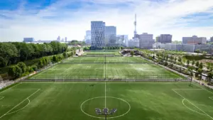 Šiuolaikiškas futbolo aikštynas su miesto panorama fone, skirtas aktyviam laisvalaikiui.