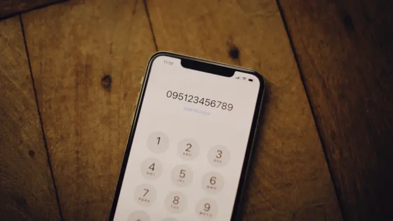 Išmanusis telefonas su atvertu numerio rinkimo ekranu padėtas ant medinio stalo paviršiaus.