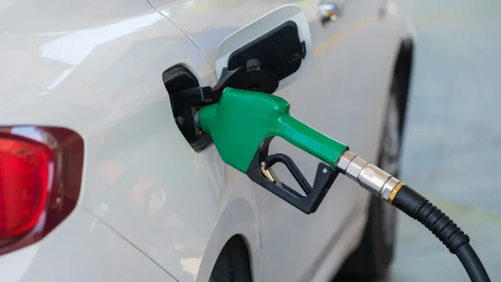 Degalų pylimo pistoletas įstatytas į balto automobilio kuro baką degalinėje