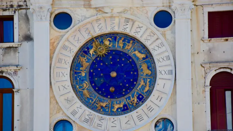 Senovinis astronominis laikrodis su zodiako ženklais ir žvaigždžių žemėlapiu ant sienos.