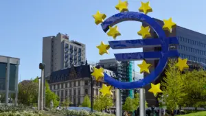 Didelis euro simbolis su žvaigždėmis Europos centrinio banko būstinės aplinkoje dienos šviesoje.