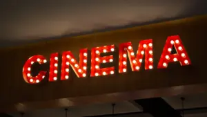 Šviečianti iškaba su užrašu „Cinema“ moderniame kino teatre su apšvietimu.