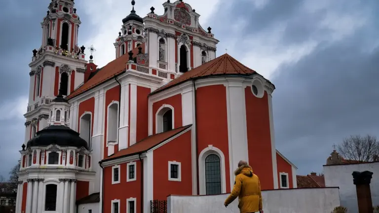 Žmogus su geltona striuke eina pro Šv. Kotrynos bažnyčią Vilniaus senamiestyje.