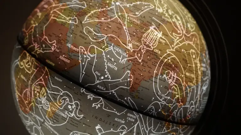 Tamsus gaublys su pavaizduotais žvaigždynais ir astrologiniais Zodiako ženklais.