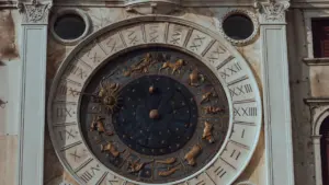 Didelis istorinis astronominis laikrodis ant pastato fasado su Zodiako ženklais ir romėniškais skaičiais.