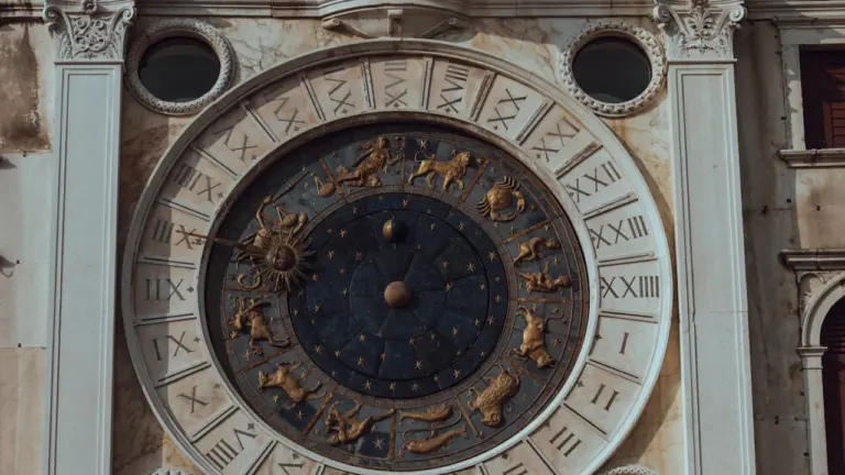 Didelis istorinis astronominis laikrodis ant pastato fasado su Zodiako ženklais ir romėniškais skaičiais.