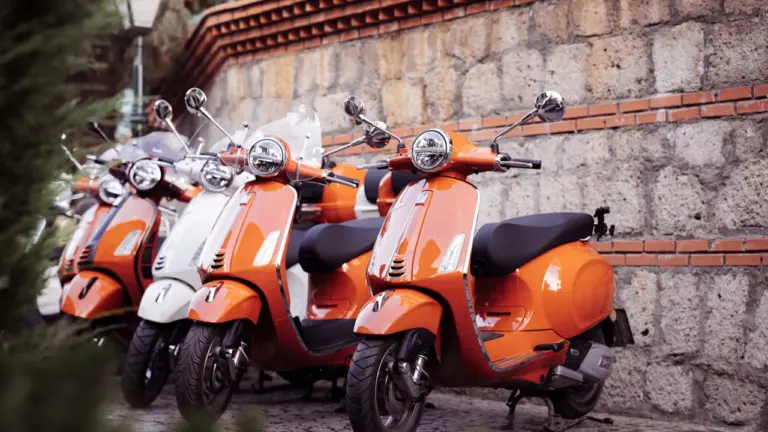 Ryškūs motoroleriai tvarkingai pastatyti akmenimis grįstoje miesto gatvėje judumo savaitės metu.