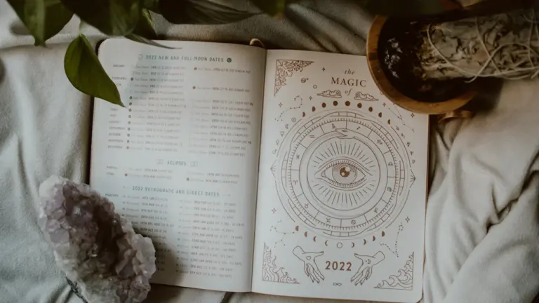 Atversta knyga su astrologiniais simboliais, kristalais ir ramia nuotaika sekmadieniui.